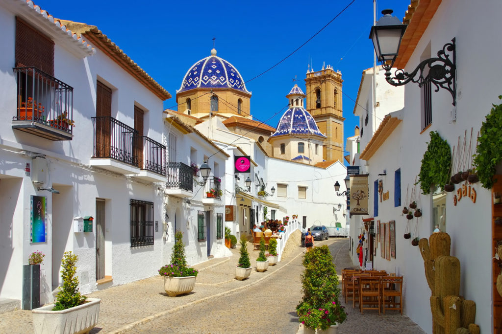A cobbled lane in Altea old town leading up to the blue-tiled domes of the Nuestra Señora del Consuelo church