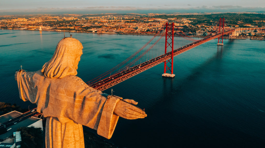 Cristo Rei statue above the 25 de Abril bridge and Lisbon at sunset