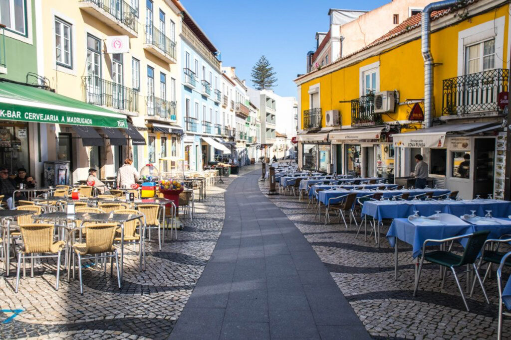 A cobbled street lined with restaurant tables near Cacilhas and Almada