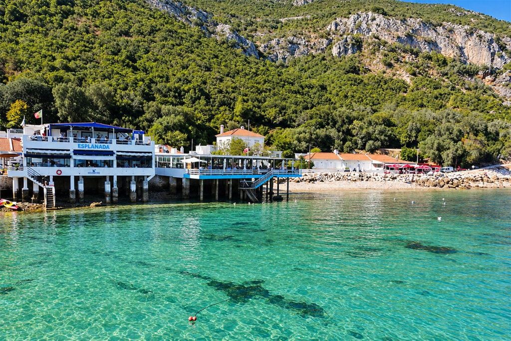 A waterside restaurant over the clear turquoise water of Portinho da Arrábida