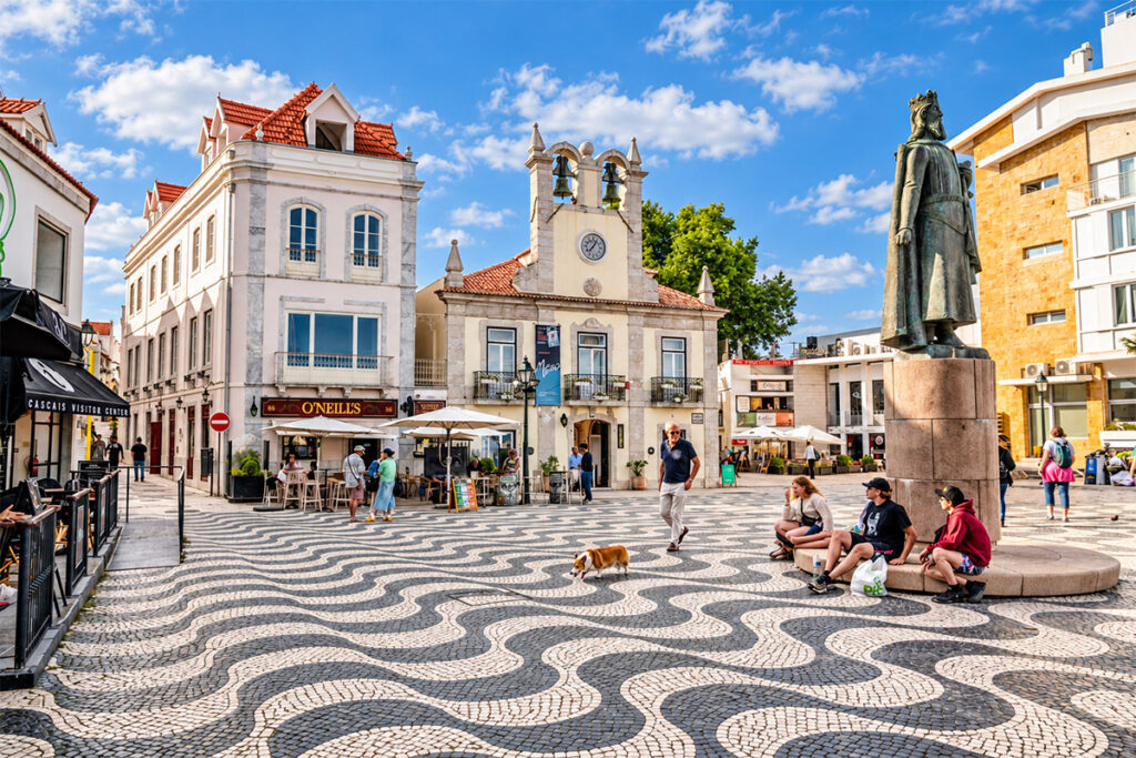 Der wellenförmig gepflasterte Hauptplatz von Cascais, mit dem alten Rathaus und einer Statue