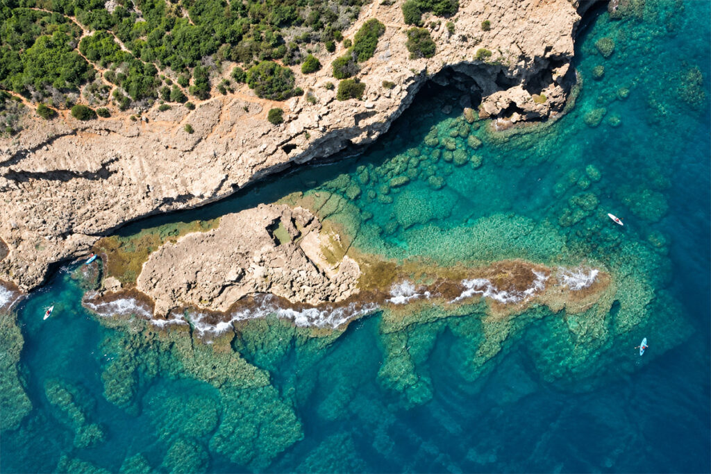 Aerial view of the Cova Tallada coastline, kayakers paddling over the clear water
