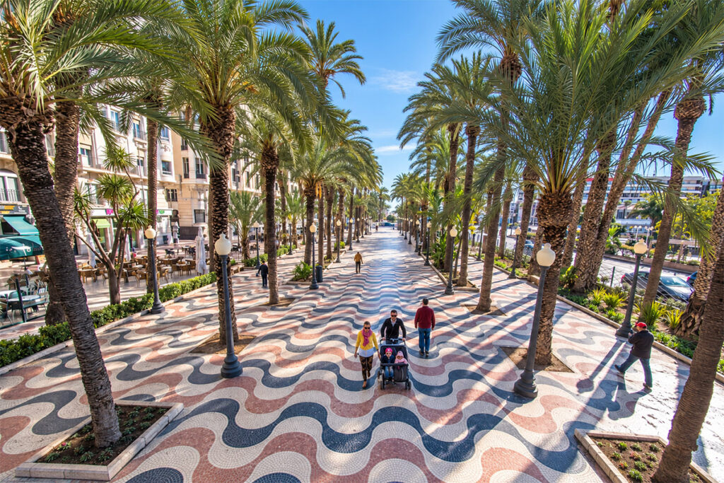 El paseo de mármol con dibujo de olas de la Explanada de España, a la sombra de las palmeras