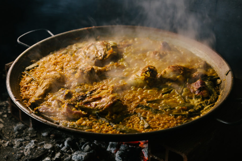 A traditional Valencian paella cooking over wood coals