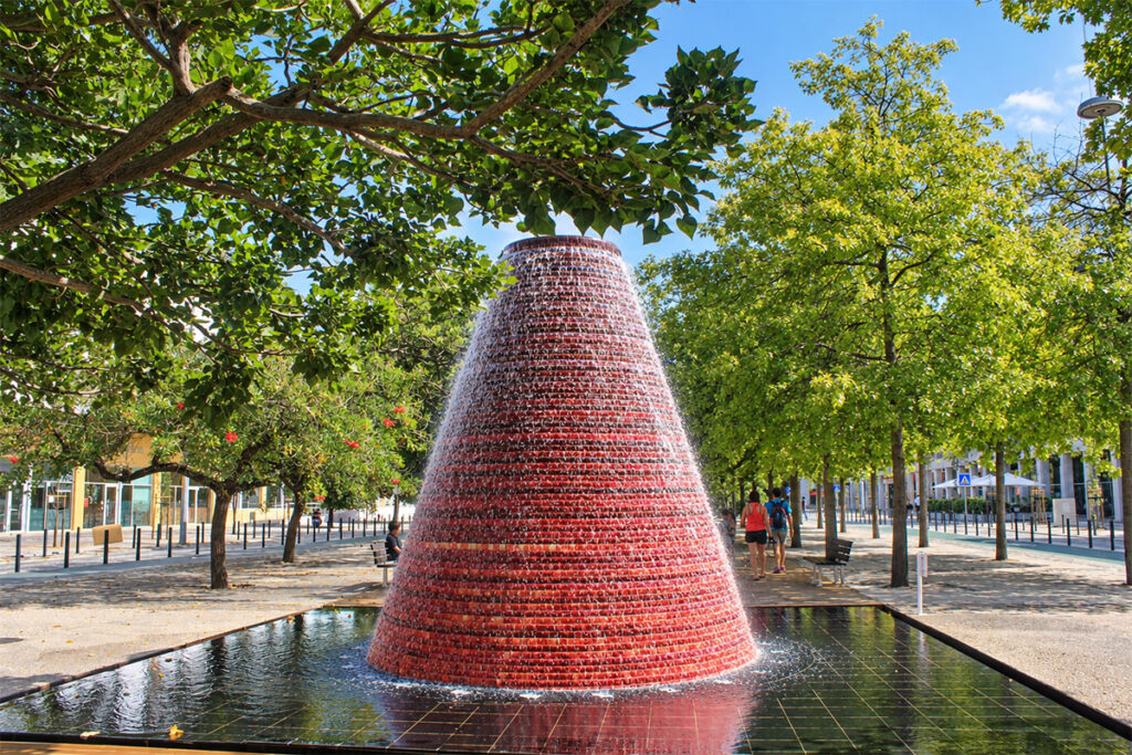 The red cone fountain among the trees of the Parque das Nações gardens