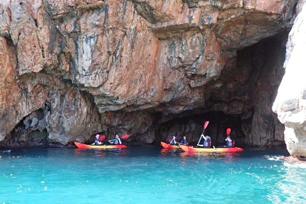 Kayakers exploring a sea cave among the rocks near Punta Negra