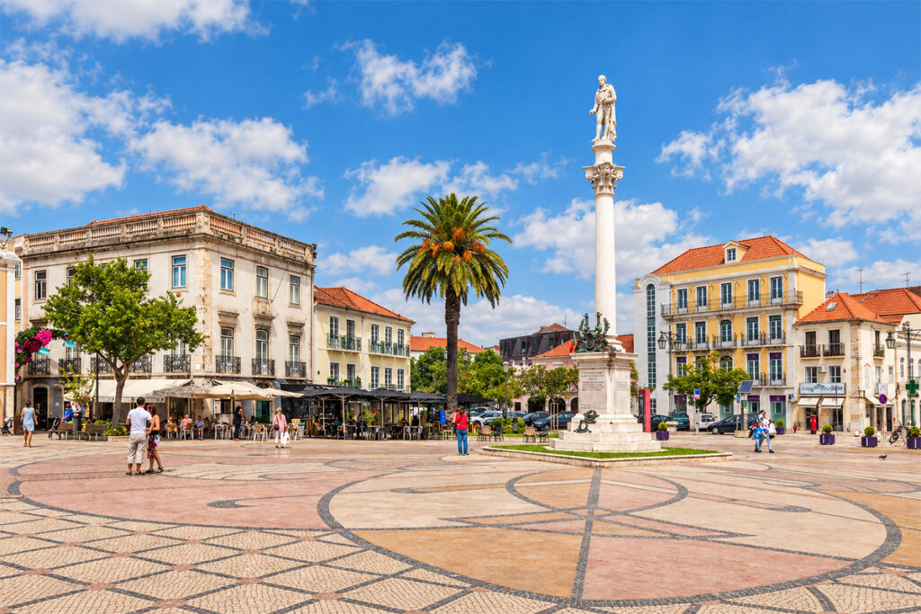The palm-shaded main square of Setúbal, with its column and statue