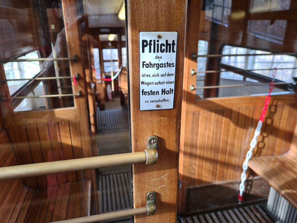 The polished teak interior of a Standseilbahn car, with an original enamel notice