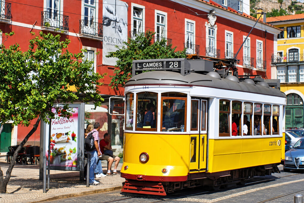 A yellow Remodelado tram, line 28, stopped in a Lisbon street